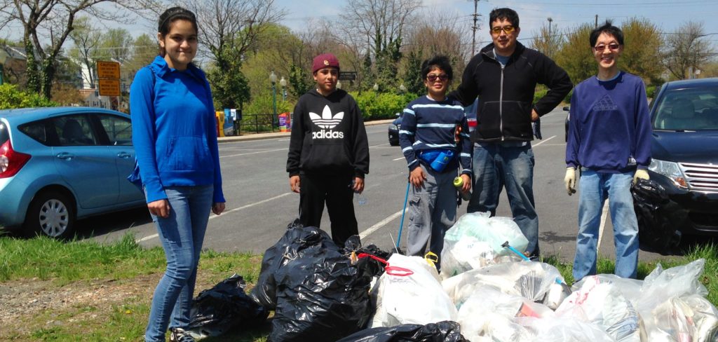Five volunteers standing next to all the trash they picked up from a stormwater facility.