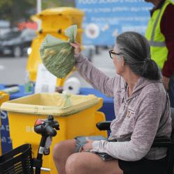 Lady dropping off her food scraps for recycling at a farmers market.