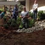 RainScapes Professionals training attendees smiling at camera while planting native plants.