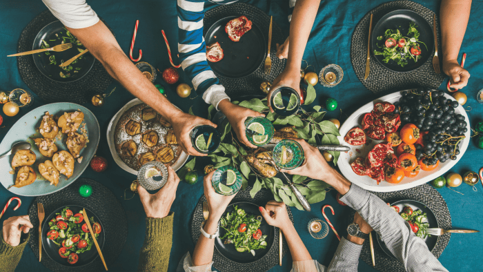 group of people in a circle cheering with drinks above a table with food