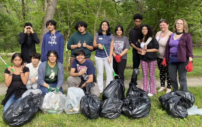 High school students pose in front of bags full of trash to show off all the litter they collected during a cleanup.